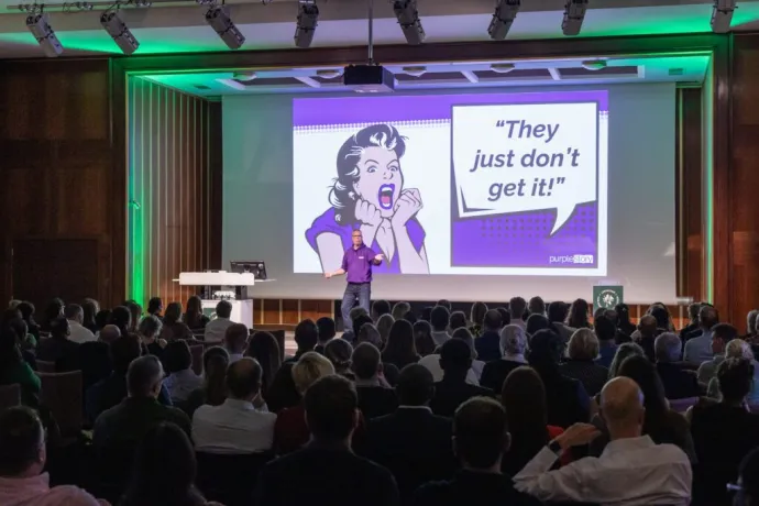 speaker on stage lecturing a crowd